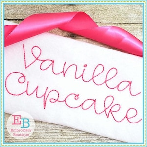 May include: Embroidered design on white fabric with pink thread. The design reads "Vanilla Cupcake".