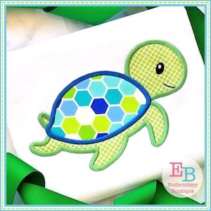 May include: Green and blue applique embroidery design of a turtle with a patterned shell. The design is on a white fabric background.