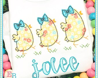 May include: Three yellow chicks with blue bows and floral patterns walking on green grass with the name "jolee" embroidered in blue cursive lettering.