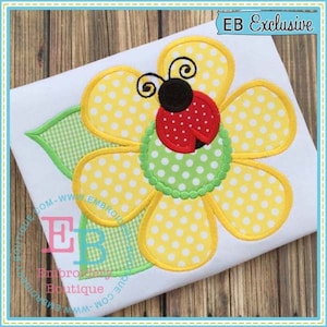 May include: A yellow flower with white polka dots and a red ladybug in the center. The flower has five petals and is outlined in yellow. The ladybug has black spots and a green leaf behind it.