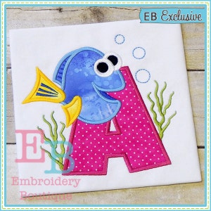 May include: Embroidered design featuring a pink letter A with white polka dots, a blue fish with yellow fins, and green seaweed. The design is on a white fabric background. The text "EB Exclusive" is in the top right corner.