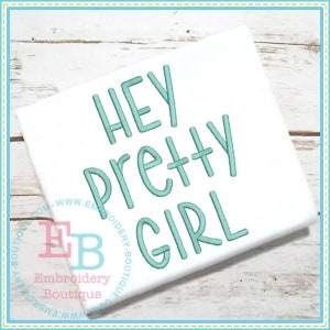 May include: A white t-shirt with the text "HEY PRETTY GIRL" embroidered in teal blue.