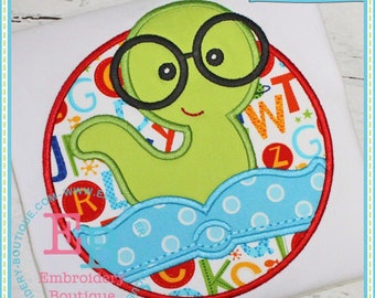 May include: A green monster wearing glasses and a blue swim cap with white polka dots. The monster is surrounded by a red circle with a colorful alphabet pattern inside.