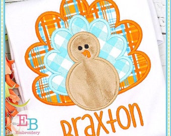 May include: Applique design featuring a brown turkey with a blue and orange plaid tail feathers. The name "Braxton" is stitched in orange below the turkey.