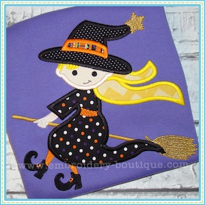 May include: Embroidered design of a witch flying on a broomstick. The witch is wearing a black hat with a yellow star, a black and white polka dot dress, and a yellow scarf. The broomstick is gold.