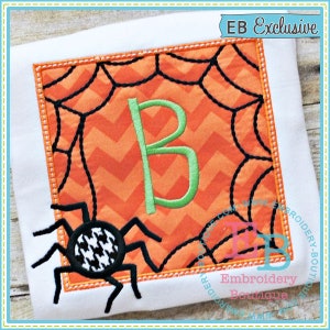 May include: Square Halloween-themed applique with an orange chevron background, black spiderweb design, and a green letter "B". A black and white houndstooth spider is in the lower left corner. The text "EB Exclusive" is in the upper right corner.