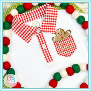 May include: White polo shirt with a red and white gingham collar and a gingerbread man applique on the pocket. The pocket has the letters "REX" embroidered on it.