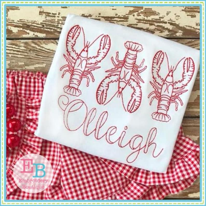 Peut inclure: T-shirt blanc avec des homards brod&eacute;s en rouge et le nom "OLLEIGH" en cursive.