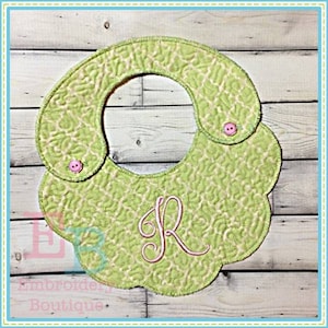 May include: A light green quilted baby bib with a floral pattern and a pink embroidered letter "R". The bib has a scalloped edge and two pink buttons. The words "Embroidery Boutique" are at the bottom.