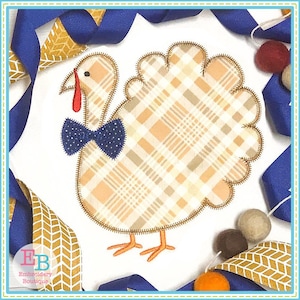 May include: Applique design of a brown and tan plaid turkey with a blue bow tie. The turkey is standing on a white background.