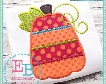 May include: White t-shirt featuring a colorful pumpkin applique. The pumpkin has a red polka dot pattern, orange polka dots, and is accented with green, blue, and orange details. The design includes a green leaf and a curly vine. The text "EB Exclusive" is visible.