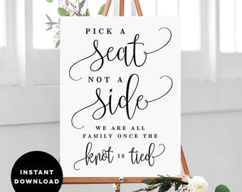 May include: A white sign with black calligraphy that reads "Pick a Seat, Not a Side. We are all family once the knot is tied."