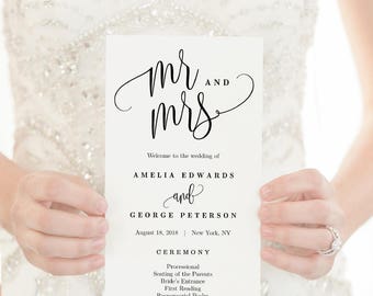 Könnte beinhalten: Ein Programm für eine Hochzeitszeremonie mit dem Text "Mr. and Mrs." in eleganter Kalligraphie. Das Programm listet die Namen des Brautpaares, Amelia Edwards und George Peterson, sowie das Datum und den Ort der Hochzeit auf: 18. August 2018, New York, NY. Das Programm enthält auch eine Liste der Zeremonie-Ereignisse, wie z. B. den Einzug, das Platznehmen der Eltern, den Einzug der Braut, die Lesungen und den Austausch der Gelübde.