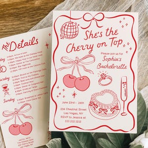 May include: Two white rectangular invitation cards with red ink illustrations and text. The main card reads She's the Cherry on Top, Sophia's Bachelorette, June 23rd-26th, 234 Chestnut Street, Las Vegas, NV, RSVP to Jessica at 555 212.1212.