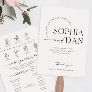 May include: Two ivory wedding fans with wooden handles. One fan displays a wedding timeline with icons, the other features the names "Sophia and Dan" and event details. The fans are part of a wedding stationery set.