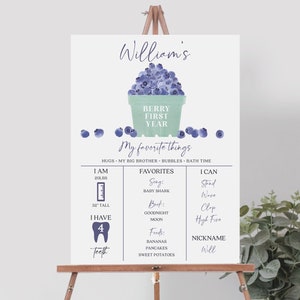 Könnte beinhalten: Ein personalisiertes Meilensteinschild 'Berry First Year' auf einer Staffelei. Das Schild zeigt eine Blaubeer-Illustration und listet die Lieblingsdinge des Kindes auf, darunter Lieder, Bücher und Lebensmittel. Es enthält auch die Größe, das Gewicht und den Spitznamen des Kindes.
