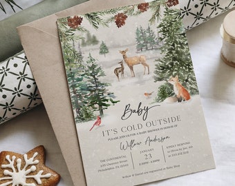 Op de afbeelding: Een winterthema baby shower uitnodiging met een aquarel illustratie van herten, een vos en vogels in een besneeuwd bos. De uitnodiging bevat de tekst "Baby It's Cold Outside" en evenement details. Een sneeuwvlok koekje is ook aanwezig.