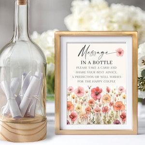 Könnte beinhalten: Ein Schild mit dem Text "Message in a Bottle" und einem floralen Design. Das Schild fordert die Gäste auf, eine Nachricht für das glückliche Paar zu schreiben.