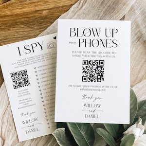 May include: Two white cards with black text. One says "I Spy" with a list of photo prompts and a QR code. The other says "Blow Up Our Phones" with a QR code. Both cards say "Thank you, Willow and Daniel."
