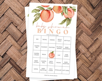 May include: Peach-themed baby shower bingo card with a watercolor illustration of peaches and leaves. The card has a grid with 25 squares, each containing a baby-related item, such as a bib, blanket, pacifier, stuffed animal, baby shampoo, diaper cream, book, hat, crib sheet, baby lotion, diaper bag, bath towel, socks, baby monitor, wipes, baby bathtub, high chair, stroller, and gift card. The card also includes the text "baby shower bingo" and "five in a row wins!"