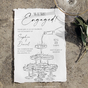 Könnte beinhalten: Eine schwarz-weiße Verlobungsankündigung mit dem Text "We're Engaged!" und Details für Sophias und Daniels Feier. Das Design beinhaltet eine Champagnerturm-Illustration und Veranstaltungsinformationen.