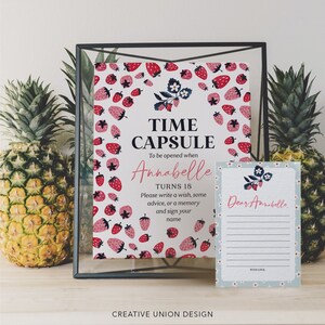 May include: A white card with a strawberry pattern and the text "Time Capsule" and "To be opened when Annabelle turns 18".  The card also includes instructions to write a wish, some advice, or a memory and sign your name.  A blue card with white flowers and the text "Dear Annabelle" is next to the white card.