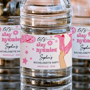 May include: Three clear plastic water bottles with pink and white labels that say "Let's stay hydrated" and "Sophin's Bachelorette Party" with a pink cowboy boot and hat graphic.