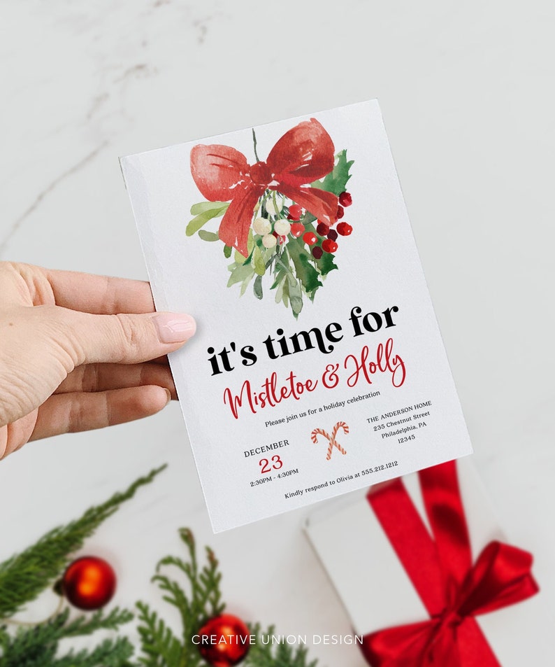 Op de afbeelding: Een witte kerstuitnodiging met een aquarel illustratie van maretak en hulst, en een rode strik. De tekst luidt "it's time for Mistletoe & Holly" en bevat evenementdetails. De uitnodiging wordt door een hand vastgehouden.