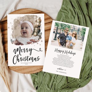 May include: Two holiday cards with family photos. One card says "Merry Christmas" with a baby photo and snowflakes. The other says "Happy Holidays" with a family photo. Both cards are on a wooden tray.