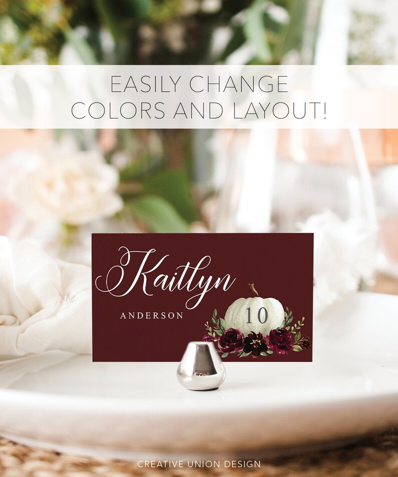 May include: A burgundy place card with the name "Kaitlyn" in elegant script, a white pumpkin illustration, and the number 10. The card is decorated with floral accents and sits on a white plate. The text "EASILY CHANGE COLORS AND LAYOUT!" is at the top.