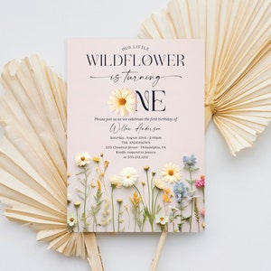 May include: A pink and white invitation with a floral design. The text reads "Our Little Wildflower is turning One" and includes the name "Willow Anderson" and details for a first birthday party.