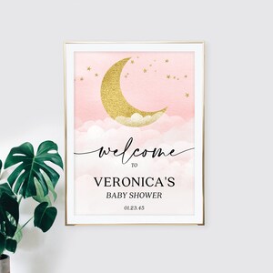 May include: A rectangular sign in a gold frame featuring a pink watercolor sky with a gold glitter crescent moon, clouds, and stars. The text reads: welcome TO VERONICA'S BABY SHOWER 01.23.45. The design uses a mix of script and serif fonts.
