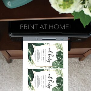 May include: Two printable baby shower invitations with a tropical theme. The invitations feature a gold frame with green tropical leaves and the text "oh baby" in black script.
