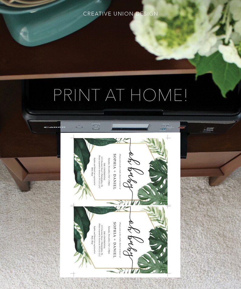 May include: Two printable baby shower invitations with a tropical theme. The invitations feature a gold frame with green tropical leaves and the text "oh baby" in black script.