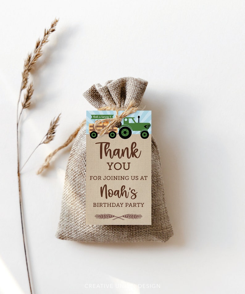 Op de afbeelding: Een kleine jute cadeauzak met een label met de tekst "Bedankt" voor Noah's verjaardagsfeestje. Het label heeft een groene tractorafbeelding en de tekst "Noah wordt 4". Het label is met touw aan de zak bevestigd.