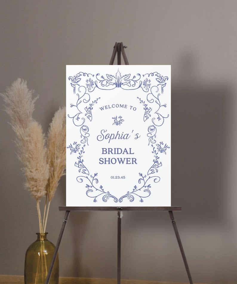May include: White sign with a blue floral border and the text "Welcome to Sophia's Bridal Shower 01.23.45".