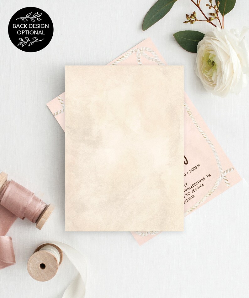 May include: A blank ivory card with a subtle watercolor texture. The card is surrounded by pink and white decorative paper with a rope design. The card is perfect for a wedding invitation or announcement.