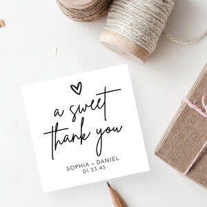 K&ouml;nnte beinhalten: Eine wei&szlig;e Karte mit schwarzer Kalligrafie, auf der "a sweet thank you" mit einem kleinen Herzen &uuml;ber dem Text steht. Unter dem Text steht "Sophia + Daniel 01.23.45"