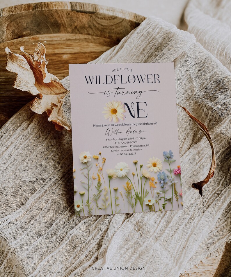 May include: A light purple invitation with a floral design. The text reads "Our Little Wildflower is turning One. Please join us as we celebrate the first birthday of Willow Anderson. Saturday, August 23rd, 2:00pm. The Anderson's, 235 Chestnut Street, Philadelphia, PA. Kindly respond to Jessica at 555.212.1212. Creative Union Design."