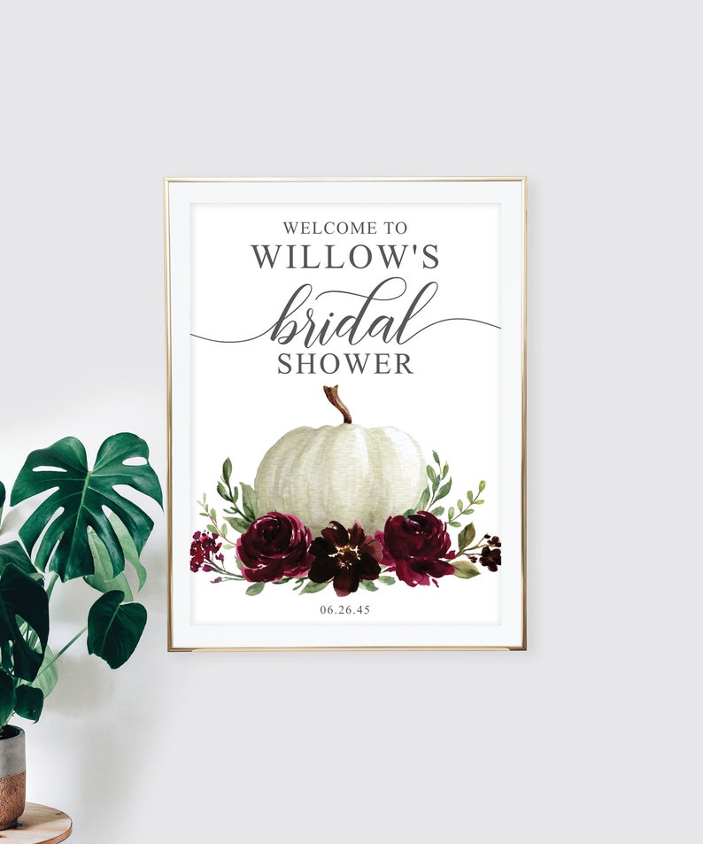 May include: A white pumpkin with a burgundy floral arrangement and the text "Welcome to Willow's bridal shower 06.26.45" on a white background.