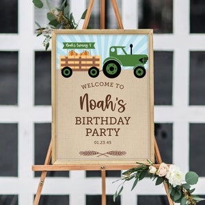 K&ouml;nnte beinhalten: Gerahmtes Schild auf einer Staffelei mit Bauernhof-Motiv. Auf dem Schild steht "Willkommen zu Noahs Geburtstagsparty" mit einem Traktor und K&uuml;rbis-Grafik. Das Schild ist mit Blumen und Gr&uuml;n geschm&uuml;ckt.