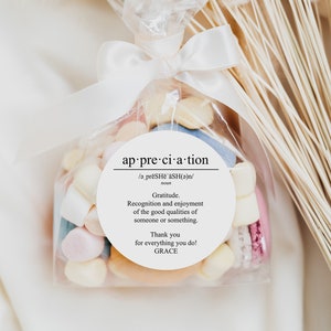 May include: A white favor bag filled with colorful candies and macarons. A white circle sticker with the word "appreciation" and a definition of the word is attached to the bag. The sticker also includes the text "Thank you for everything you do! GRACE".
