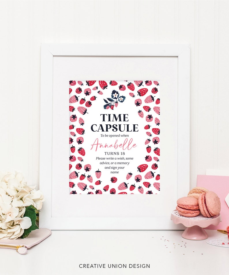 May include: A white framed sign with a strawberry pattern. The sign says "Time Capsule" and "To be opened when Annabelle turns 18. Please write a wish, some advice, or a memory and sign your name."