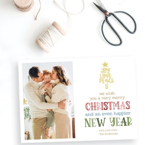 May include: A rectangular holiday greeting card featuring a photograph of a family of three on the left and text on the right. The text reads: JOY LOVE PEACE, we wish you a very merry CHRISTMAS and an even happier NEW YEAR with love from, The Andersons.