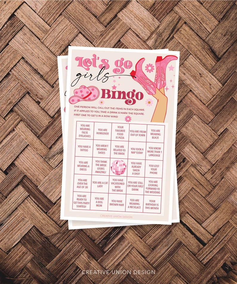 May include: A pink and white bingo card with the text "Let's go girls Bingo" at the top. The card has a variety of squares with different prompts for a bridal shower game. The card features a pink disco ball in the center.
