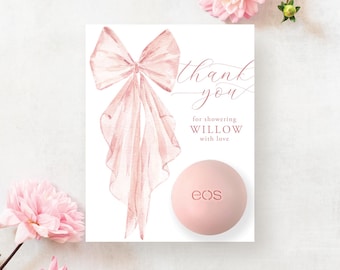 May include: A blush-colored EOS lip balm next to a white card with a watercolor bow and the words "thank you" and "for showering Willow with love." Pink flowers are scattered around the card.