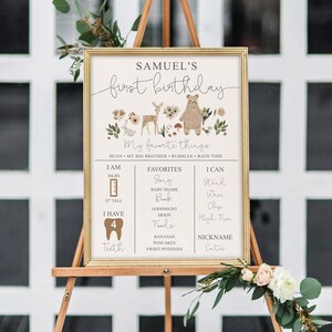 May include: A printable first birthday sign for a boy named Samuel. The sign features a woodland theme with a deer, bear, and rabbit. It includes details about the child's age, weight, height, favorite things, and what they can do. The sign is decorated with floral elements.