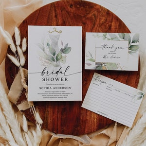May include: A bridal shower invitation with a watercolor design of a dress, greenery, and gold accents. The invitation includes the text "bridal shower", "Sophia Anderson", and the date and time of the event. There is also a thank you card with the text "Thank you from the future Mrs. Anderson" and a recipe card with the text "Recipe".