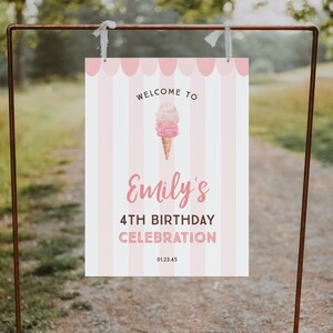 May include: A pink and white striped welcome sign for Emily's 4th birthday celebration. The sign features an ice cream cone graphic and the text "Welcome to Emily's 4th Birthday Celebration 01.23.45". The sign is hanging on a brown metal frame.