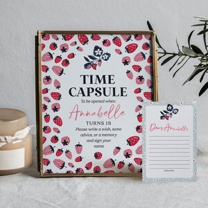 May include: A white card with a strawberry pattern and the text "Time Capsule" and "To be opened when Annabelle turns 18".  The card also includes instructions to write a wish, some advice, or a memory and sign your name.  A second card with a strawberry pattern and the text "Dear Annabelle" is also shown.